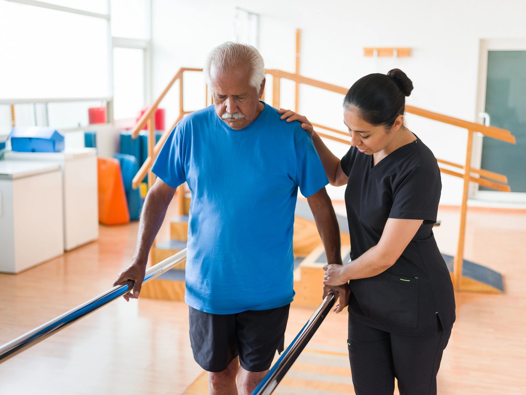 Therapy support helping a senior practice walking